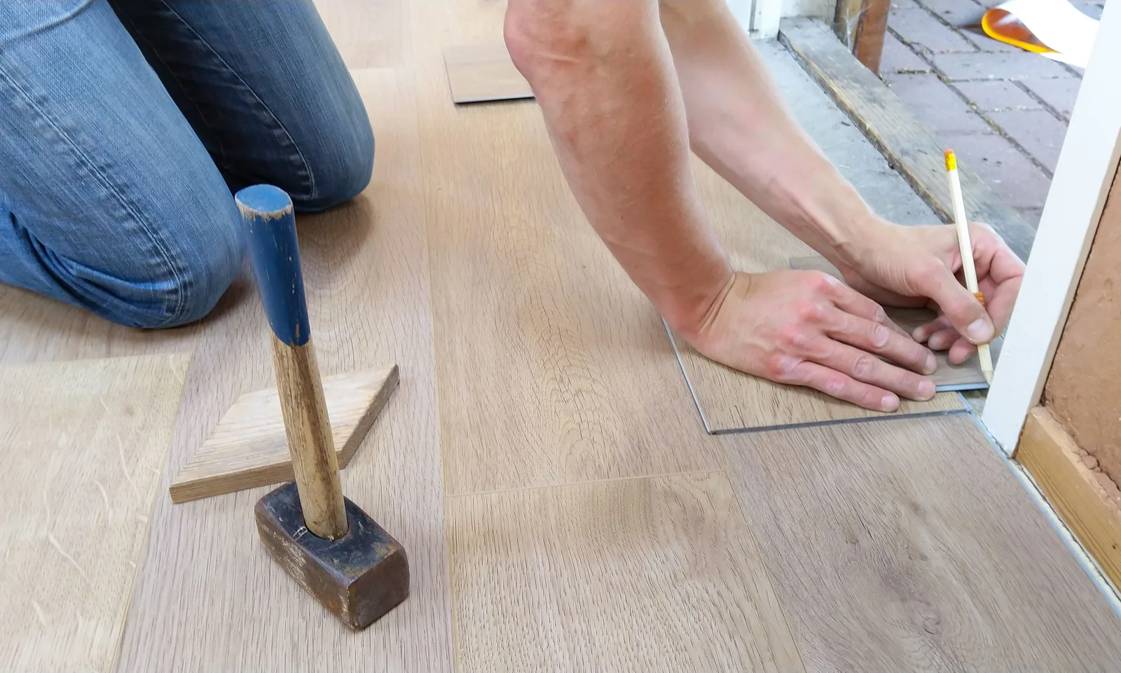 Handwerker von Lomi-Bau beim sorgfältigen Verlegen eines Holzbodens