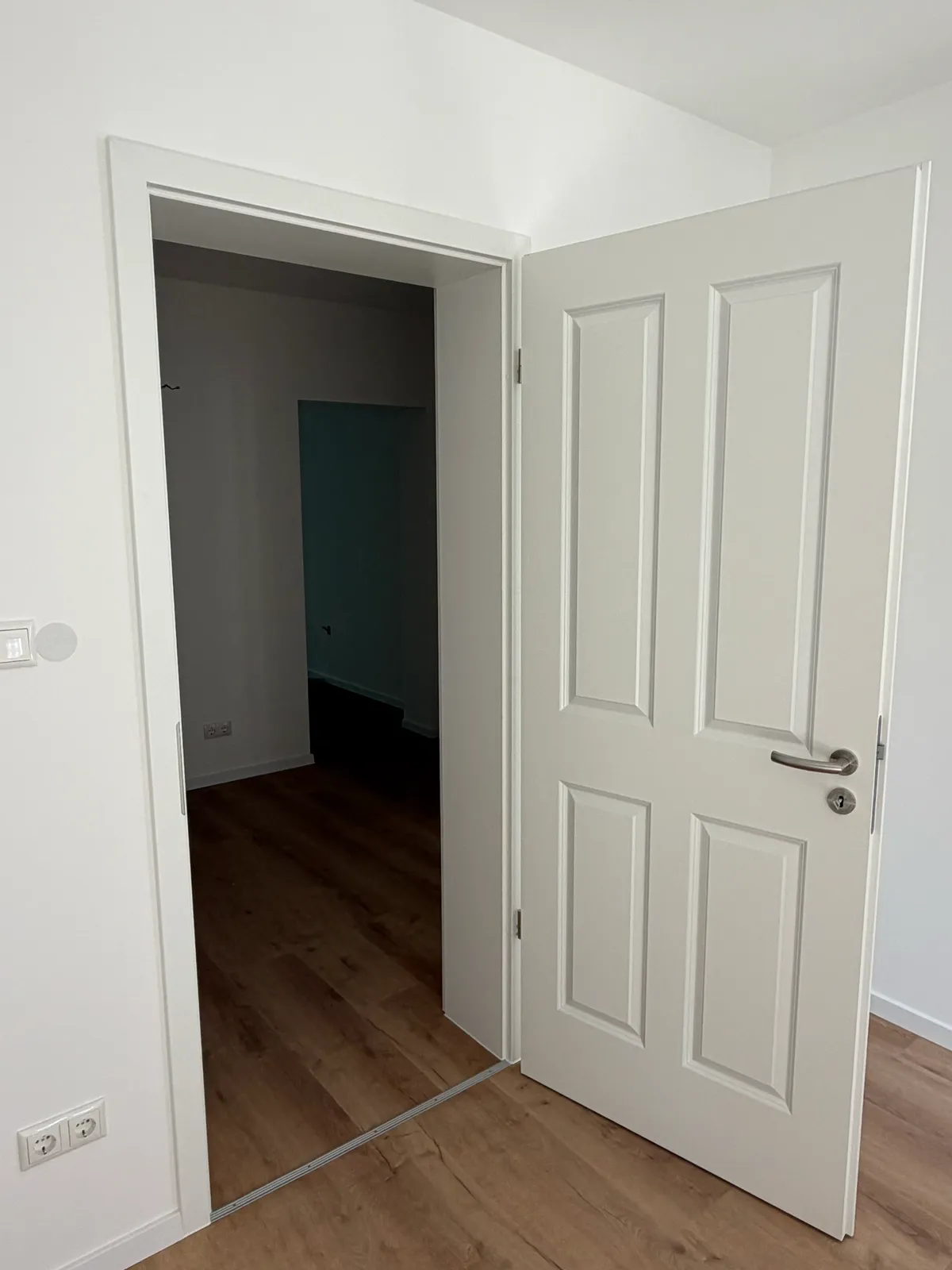 Offene Zimmertür, dahinter ein Raum mit grüner Wand — Lomi-Bau